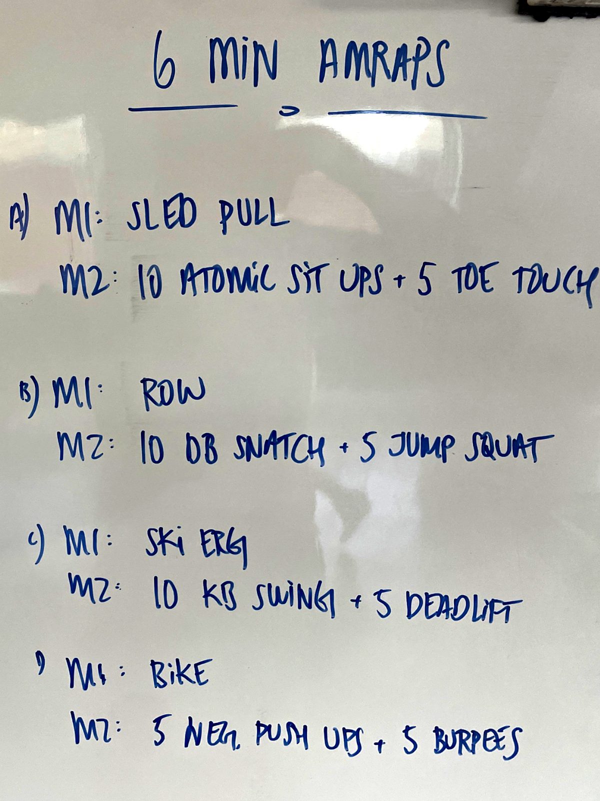 Tavle: 6 min. AMRAPs – fire runder med sled pull, roning, skierg og bike, hver med to øvelser.